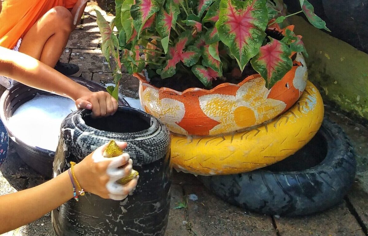 Planta de hojas rosadas y verdes en una maceta hecha con neumáticos pintados